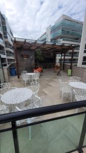 a patio with white tables and chairs in a building at Apartamento em Praia Grande - Le Bon Vivant - Arraial do Cabo in Arraial do Cabo