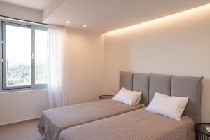 a bedroom with a bed with two pillows and a window at Sunset Luxury Villa in Akritokhórion +29 photos