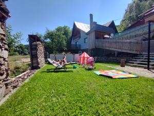 a woman sitting in a chair in a yard with a kite at Chalupa U Šindelářů - Velké Karlovice in Velké Karlovice