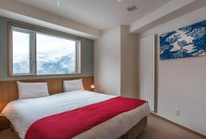 sypialnia z dużym łóżkiem i oknem w obiekcie Snow Crystal w mieście Niseko