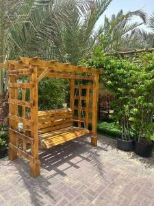 a wooden gazebo with a bench in a garden at لولي قست هاوس in Al Ain