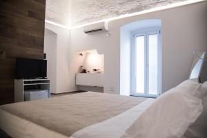 a white bedroom with a bed and a television at Il Cocchiere in Palagianello