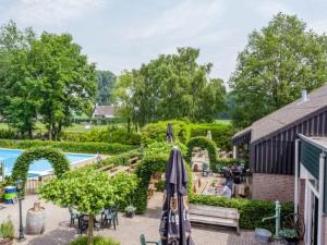 un patio al aire libre con sombrillas y una piscina en Heerlijk Huisje in het bos op Chaletpark Kempenbos en Diessen