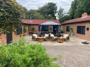 un patio con mesas y sillas y una tienda de campaña en The Garth Guest Suite Studio Cottage, en Lingfield