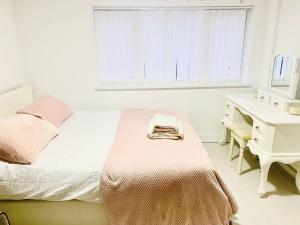 a white bedroom with a bed and a desk at Lovely one bedroom flat next to our family home in Dallington