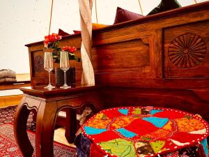 a wooden bed with a table next to a table with wine glasses at tent delhi a b&b in a luxury glamping style in Mariefred