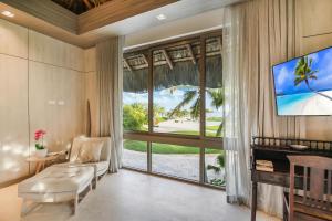 - un salon avec une grande fenêtre et une télévision dans l'établissement 5BR Cap Cana Villa with Ocean & Golf Views, Chef, Maid, Butler, Pool, Jacuzzi, and Beach Club Access, à Punta Cana