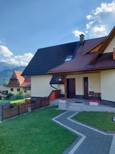 a house with a red roof and a pathway at Apartament okno na Giewont in Kościelisko