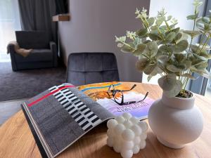 a table with a book and a vase with a plant at Apartamenty Krupówki 20 in Zakopane