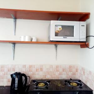 eine Mikrowelle auf einem Regal über einem Herd in einer Küche in der Unterkunft Mileslin Homes in Machakos
