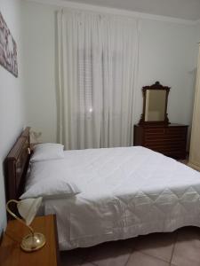 1 dormitorio con cama blanca, espejo y mesa en Casa Teresa en Tarquinia