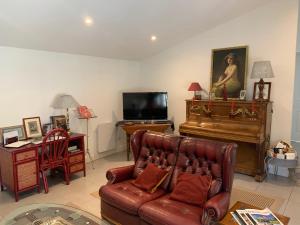 a living room with a couch and a piano at La Maison de Josephine in Montignac-Charente