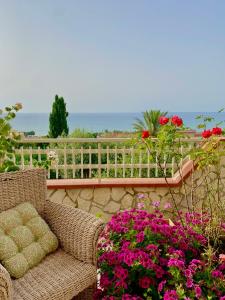 una sedia di vimini seduta su un patio fiorito di Villa Mare Giuggiola ad Alcamo Marina