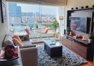 a living room with a television and a large window at Exclusivo Departamento 2BR en San Isidro in Lima