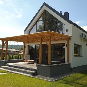 a house with a wooden pergola on a patio at Lawendowa Stodoła in AdamÃ³w