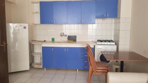kuchnia z niebieskimi szafkami, stołem i lodówką w obiekcie SARIMSAKLI RİO BEACH KARŞISI DENİZE 0 DAİRE w mieście Ayvalık