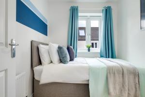 una camera da letto con un letto con tende blu e una finestra di Contractors Retreat 3 bed house, sleeps up to 7, free parking a Milton Keynes