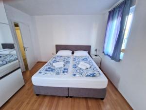 Apartments Vedran في بونات: غرفة نوم صغيرة مع سرير بملاءات زرقاء وبيضاء