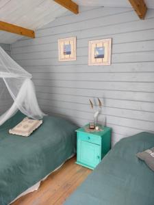 a bedroom with two beds and a night stand with a table at Metsatuule puhkeküla in Hiiumaa