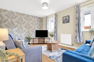 a living room with a blue couch and a tv at Contractors Retreat 3 bed house, sleeps up to 7, free parking in Milton Keynes