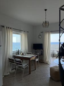 a dining room with a table and chairs and the ocean at Ninemia Apartment in Kaloi Limenes