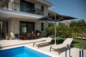 a patio with a table and chairs and an umbrella at Pietra Mare Villas in Polychrono