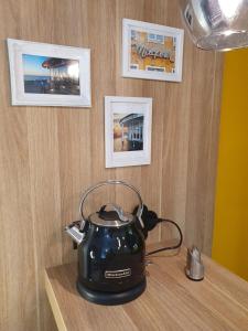 a tea kettle on a wooden table with pictures on the wall at Kleine Milchbar in Norderney