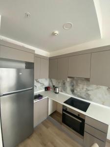 La cuisine est équipée de placards blancs et d'un réfrigérateur en acier inoxydable. dans l'établissement Luxry Apartment, à Istanbul