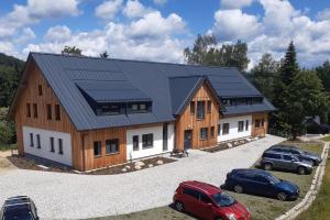 una casa con un tetto di metallo e due auto parcheggiate di Apartmán Devítka Resort pod Špičákem a Smržovka