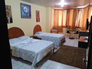 Habitación de hotel con 2 camas y mesa en Olmedo Plaza Hotel, en Guayaquil