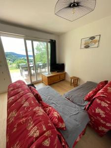 a bedroom with a bed with red pillows and a balcony at Bel appartement Magnifique vue Lac -Les Gouttridos in Gérardmer