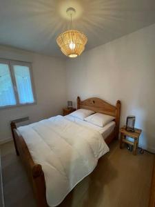 a bedroom with a large white bed and a chandelier at Bel appartement Magnifique vue Lac -Les Gouttridos in Gérardmer