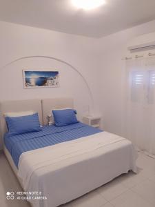 JB Villa في ميساريا: غرفة نوم بيضاء مع سرير ووسائد زرقاء