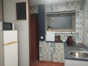 Arrifana的住宿－Bom Caminho，一个带水槽的厨房和墙上的电视