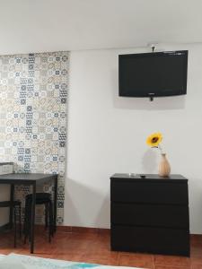 a dining room with a table and a tv on a wall at Bom Caminho in Arrifana