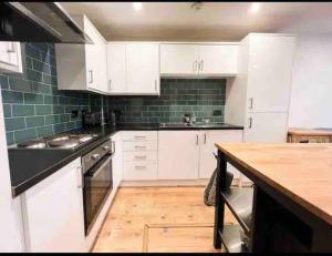 een keuken met witte kasten en een houten vloer bij Modern 2bed 2bath in Leith in Edinburgh