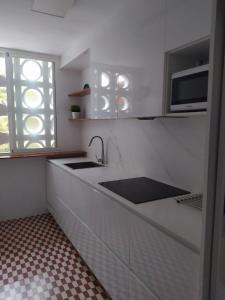a white kitchen with a sink and a microwave at Apartamento Benicassim in Benicàssim