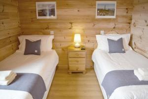 two twin beds in a room with wooden walls at Arran Lodge, Isle of Harris in Manish