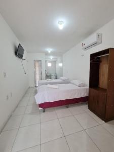 a bedroom with two beds and a television in it at Pousada Jereissati in Maracanaú