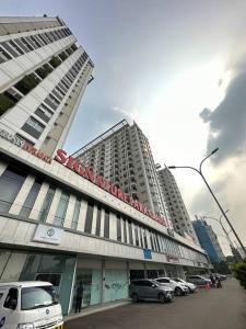 un grand bâtiment avec des voitures garées devant lui dans l'établissement Signature Park Grande Serviced Condominium LRT Jakarta 2BR, à Jakarta