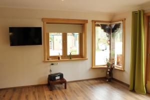 sala de estar con TV y 2 ventanas en Naturhotel Hof Ehlers, en Bergen