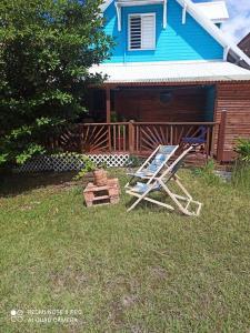 a chair sitting in the grass in front of a house at Horizons Caraïbes in Sainte-Luce