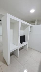 uma prateleira de livros brancos com uma televisão em Loft A em Hidalgo del Parral