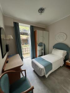 a bedroom with a bed and a desk and a chair at Hotel Excelsior Bay in Malcesine