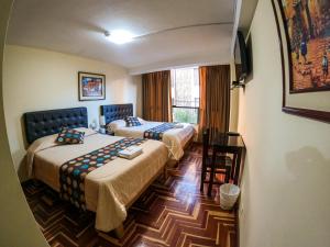 a hotel room with two beds and a window at Hotel Casa Santa Beatriz in Cusco