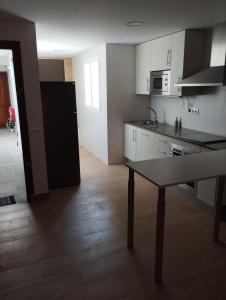 a kitchen with white cabinets and a table in it at Casa juani in Rota