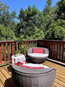 a patio with two wicker chairs and a table on a deck at Ecrins Lodge in Le Bourg-dʼOisans