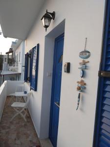 un couloir avec une porte bleue et une chaise dans l'établissement Orizodas, à Lipsi