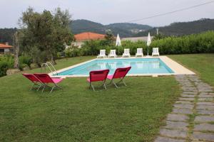 a group of red chairs and a swimming pool at Casa do Villas in Castelo de Paiva