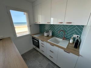 une cuisine avec un évier et une fenêtre dans l'établissement Vue mer exceptionnelle à Cabourg, à Cabourg